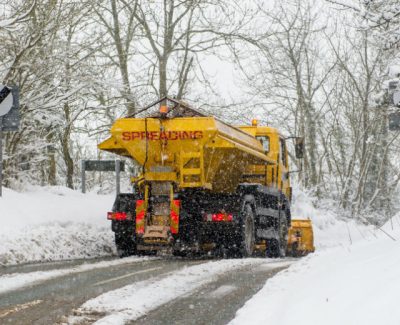 Yellow truck on snow road grit spreading