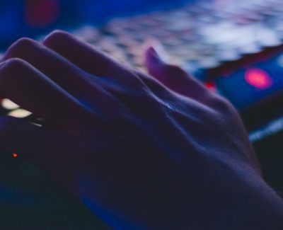 Hand on a dark keyboard with red underlighting