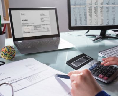 person sat with a calculator and laptop doing their tax return